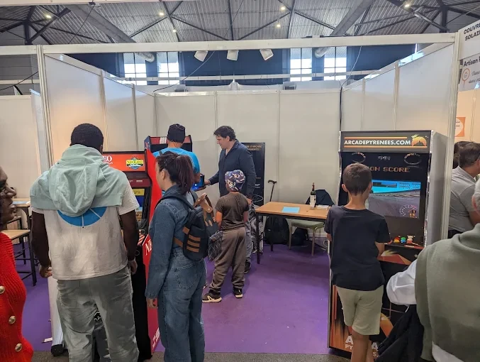 Les bornes Arcade Pyrénées sur un salon événementiel avec des visiteurs